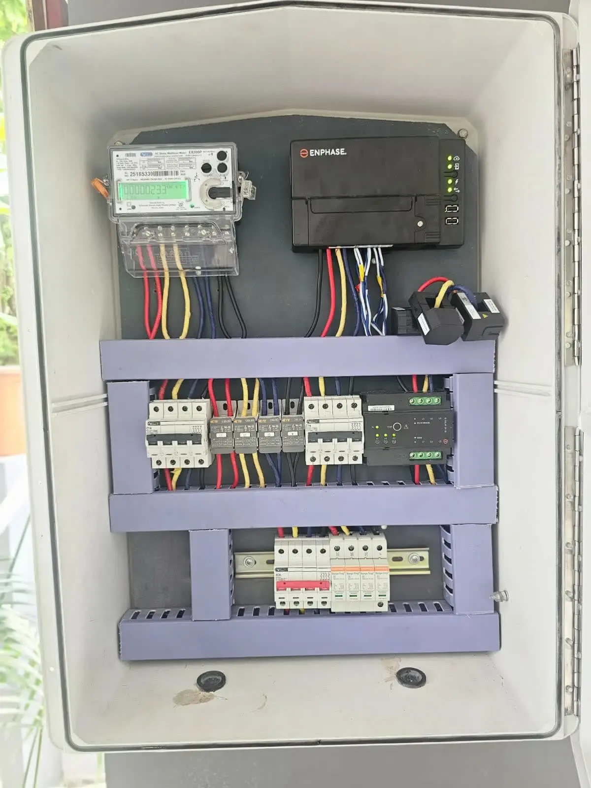 An Augzet-built distribution board: energy meter, monitoring gateway, MCBs, RCBOs, surge protection and current transformers, wired and labelled inside a weatherproof enclosure.
